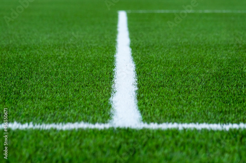 Blurry football green field with white line like "T". Selective focus. © Norexy art