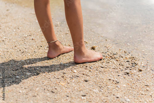 rear view of feet and legs walking on the river beach.