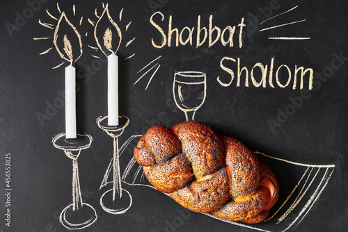 Shabbat Shalom - Jewish and Hebrew greetings. Candles and a glass of wine drawn on a chalk board next to wicker bread