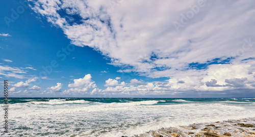 Ocean with waves and blue sky with clouds.
