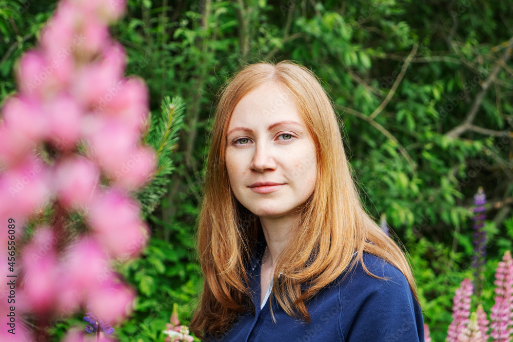 girl with red hair in the garden with lupins flowers