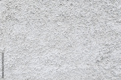 Close-up of a plastered and rough concrete or stone wall painted in white or light gray. High resolution full frame textured background. Copy space.