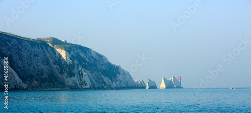 The Needles Lighthouse and White Cliffs of Allum Bay in the Isle of Wight with a hazy bright blue pale sky photo