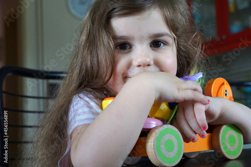 Adorable little brunette girl looking into the camera with a toy in hands photo