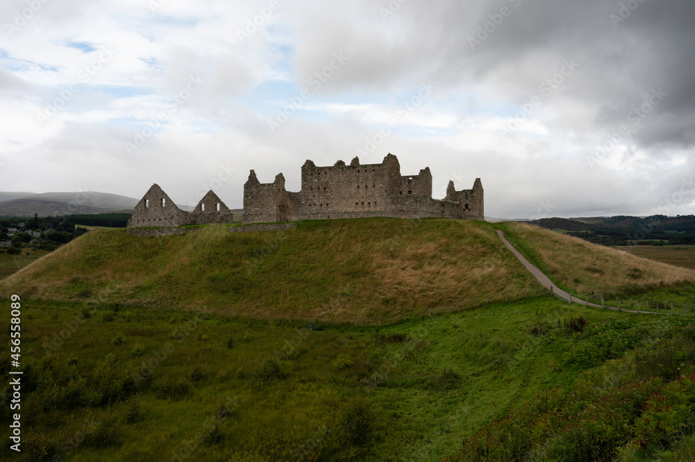 The ruins of Ruthven Barracks in the Scottish Highlands. Path leading to building which is on a hill. Blue sky and clouds, grassy area. Used as barracks for English during occupation of Scotland.