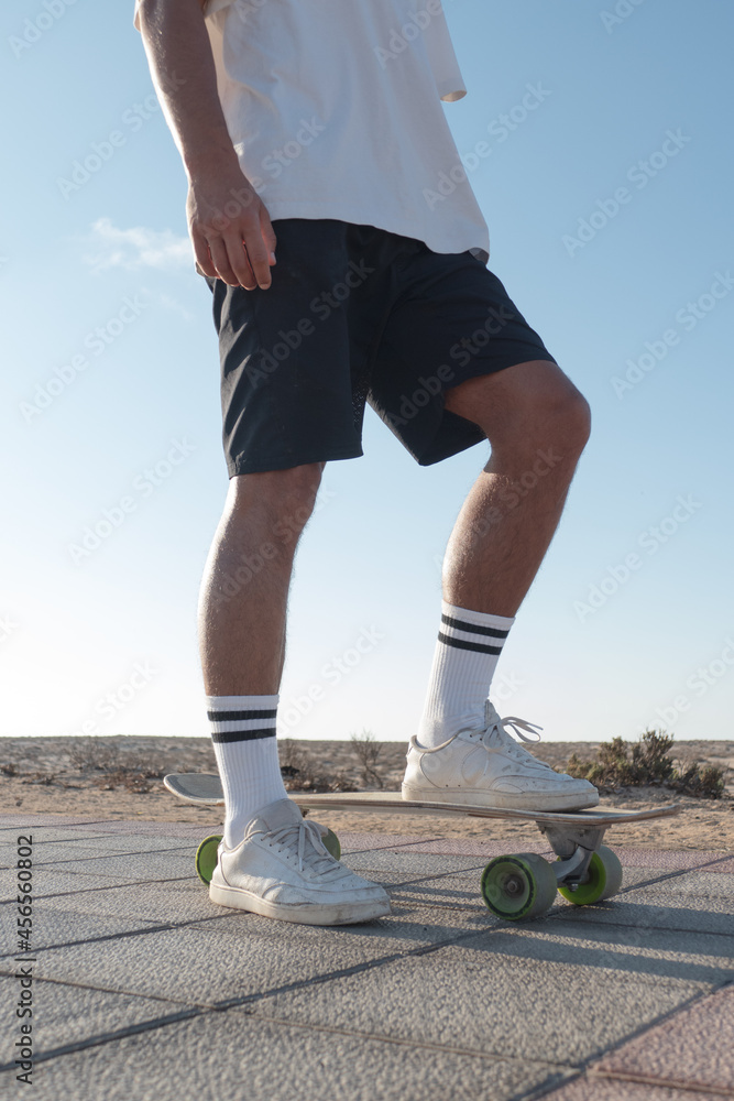 Unrecognizable stylish skater standing outdoor with his skateboard and wearing summer clothes