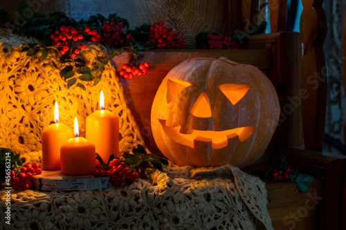 Halloween concept. Rustic Halloween card. Happy Halloween. Jack's lantern from pumpkin and candles. Pumpkin with a cut out face. Candles and rowan clusters around. Autumn orange composition. 