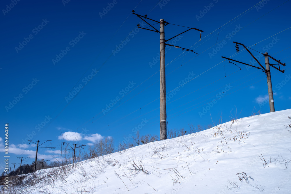 An electrified railway on an trackbed under the snow. Electric poles along the railway. An electrified railway on an trackbed under the snow. Electric poles along the railway.