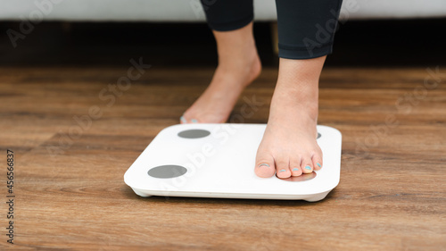 Woman leg stepping on scales at home. Measurement instrument in kilogram for diet Lose weight concept
