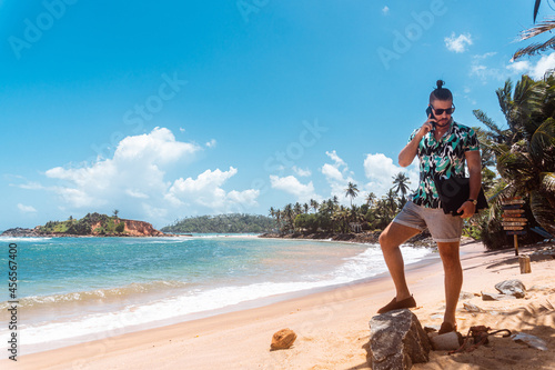Mężczyzna z laptopem i telefonem na tle tropikalnego wybrzeża