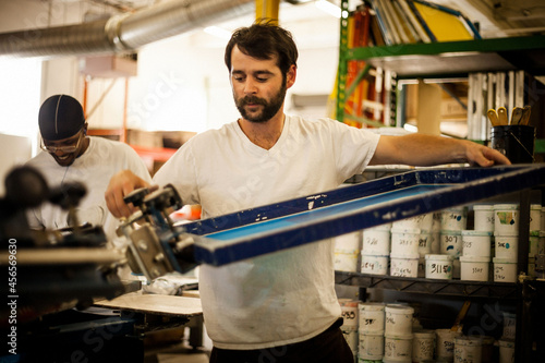 Fotografie Worker carrying frame in screen printing workshop