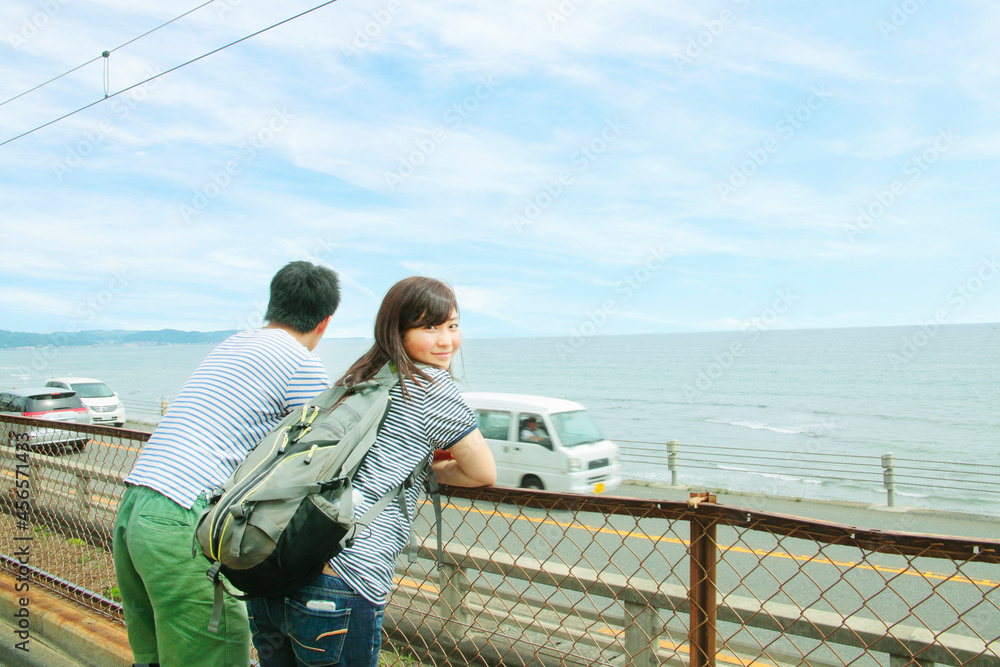 Young couple leaning against fence, looking out to sea Young couple leaning against fence, looking out to sea