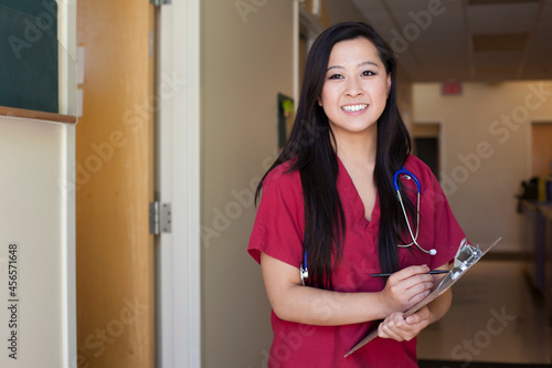 Photos Portrait of young female nurse holding clipboard