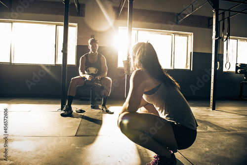 Fotografie Female trainer mentoring male client in gymnasium