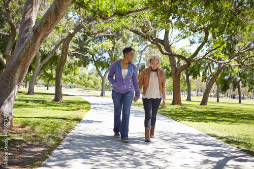 Lesbian couple holding hands and strolling in park