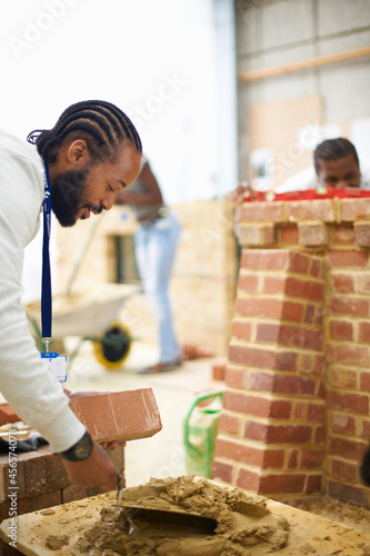Male college student using cement trowel in bricklaying workshop
