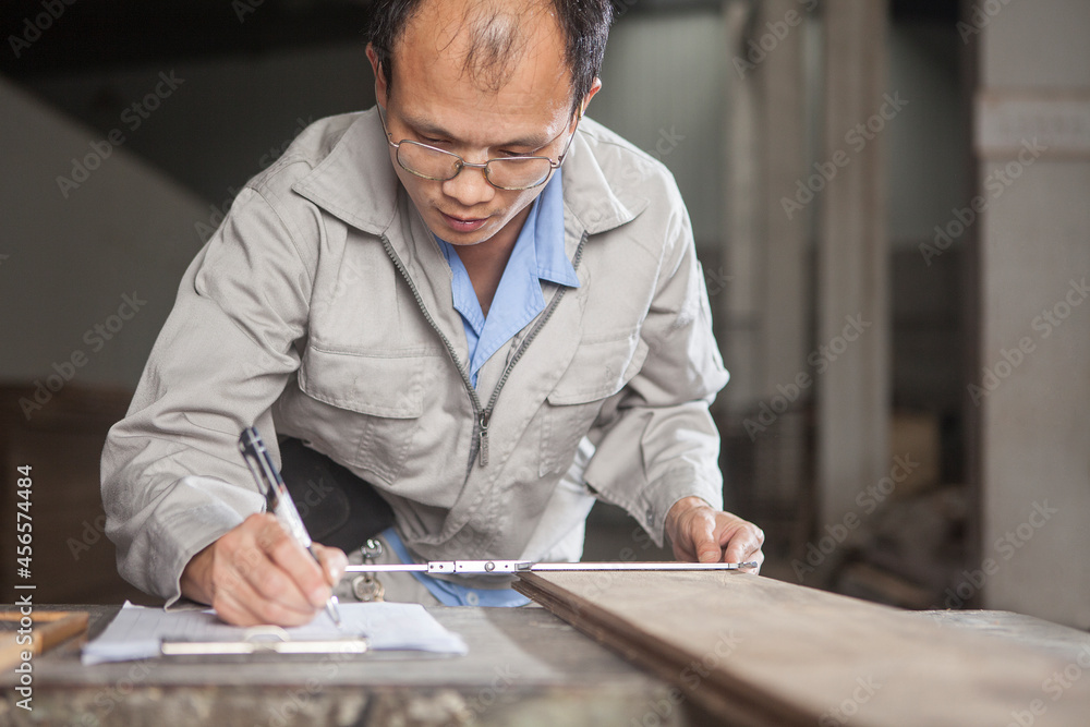 Carpenter measuring wood plank with vernier caliper in factory, Jiangsu, China Carpenter measuring wood plank with vernier caliper in factory, Jiangsu, China