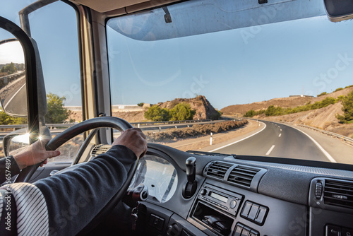 Fototapeta Naklejka Na Ścianę i Meble -  Truck driver driving on the highway, seen from inside the cab.