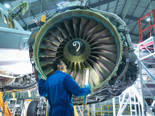 Tableau sur toile Engineer inspecting jet engine in aircraft maintenance factory