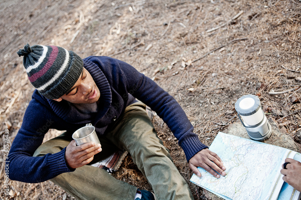 Young man with mug, looking at map outdoors Young man with mug, looking at map outdoors