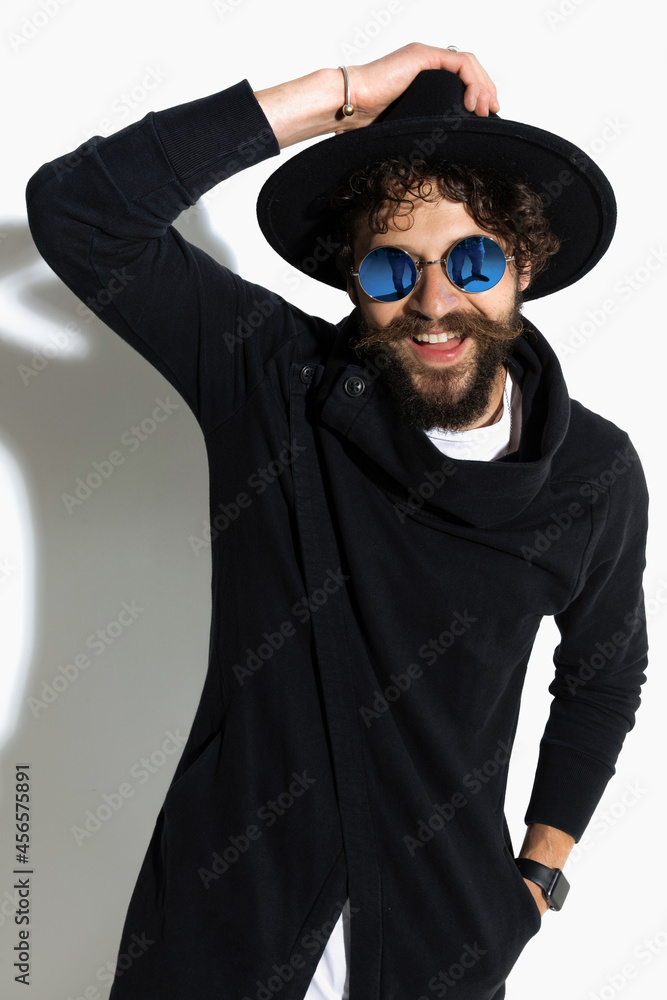 casual man holding his hat and one hand in pocket
