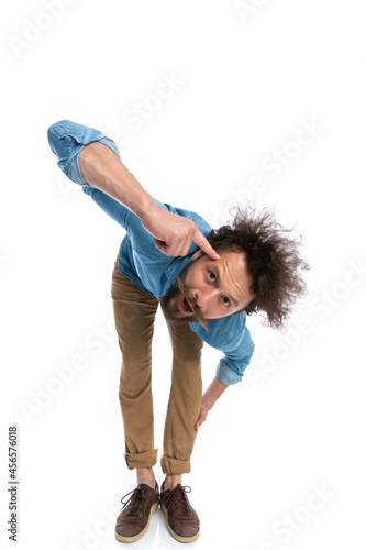 casual man leaning forward and pointing at his head
