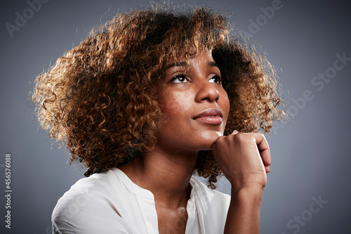 Billede på lærred Portrait of young woman, hand on chin, looking up