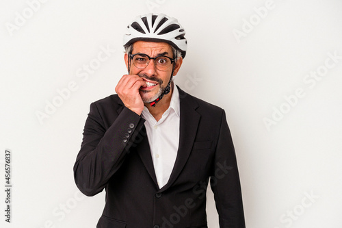 Middle age business man wearing a bike helmet isolated on blue background  biting fingernails, nervous and very anxious. © Asier