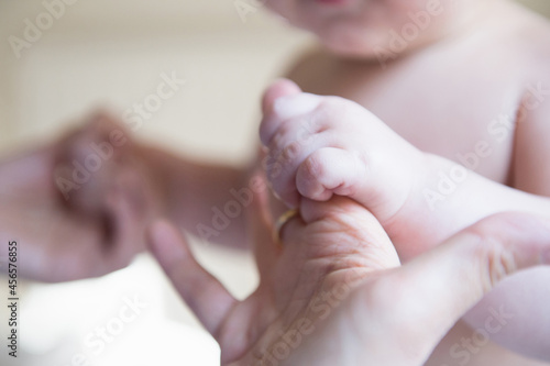 Baby boy holding mother's hands, focus on hands