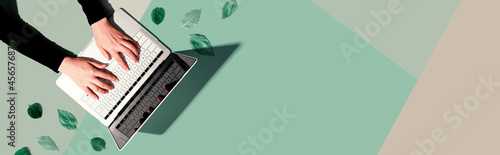 Person using a laptop computer with green leaves from above