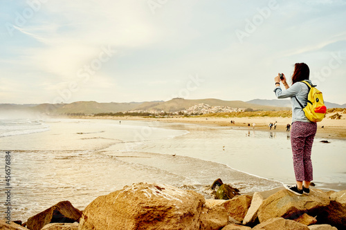 Slika na platnu Female tourist photographing sea view on smartphone, Morro Bay, California, USA