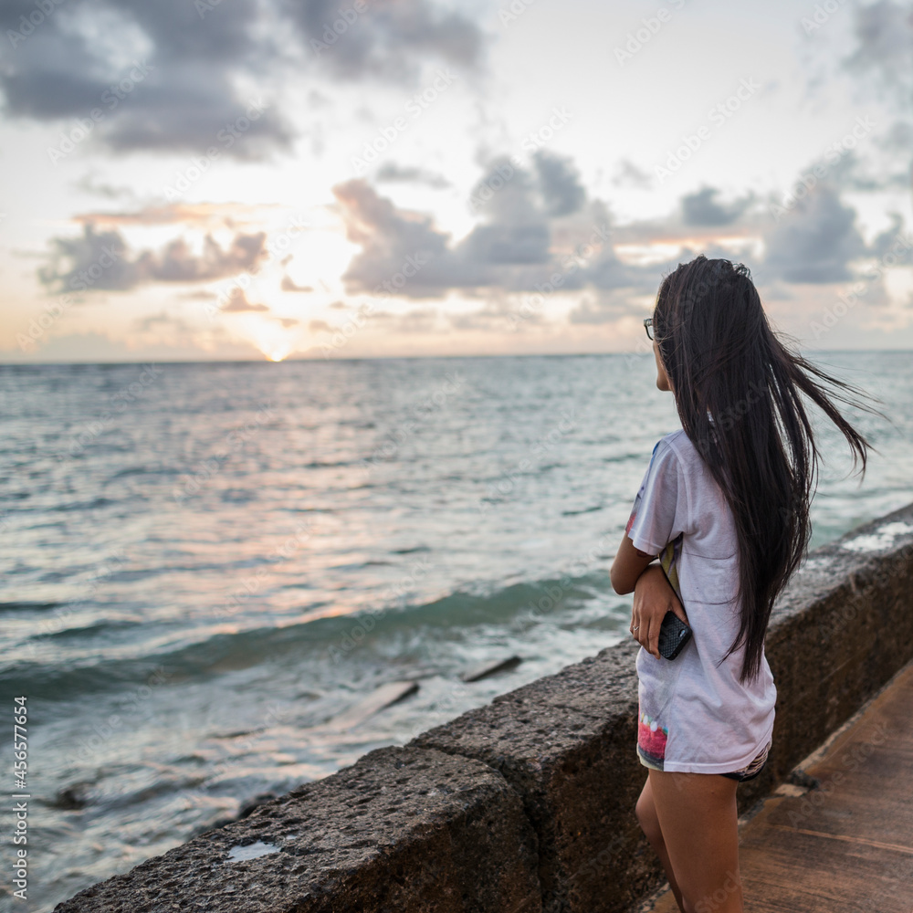 Young woman watching sunrise, Kaaawa beach, Oahu, Hawaii, USA