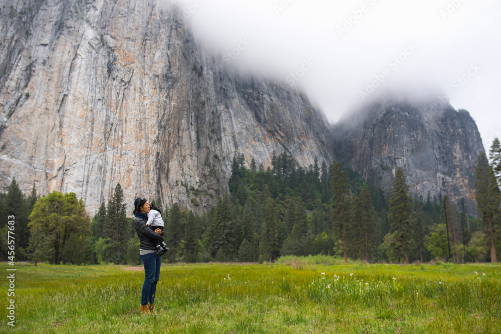 Mid adult woman carrying toddler daughter in meadow, Yosemite National Park, California, USA Mid adult woman carrying toddler daughter in meadow, Yosemite National Park, California, USA