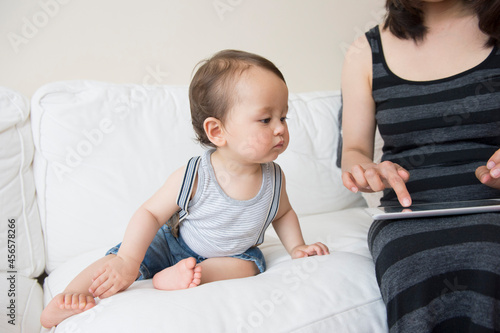 Принти на полотні Mature mother using digital tablet touchscreen watched by baby son