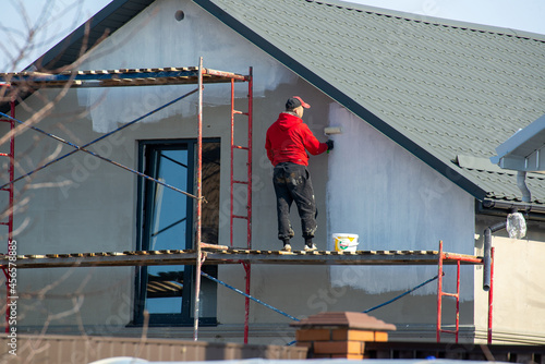 close up details of painting walls, industrial worker using roller and other tools for painting walls of new house