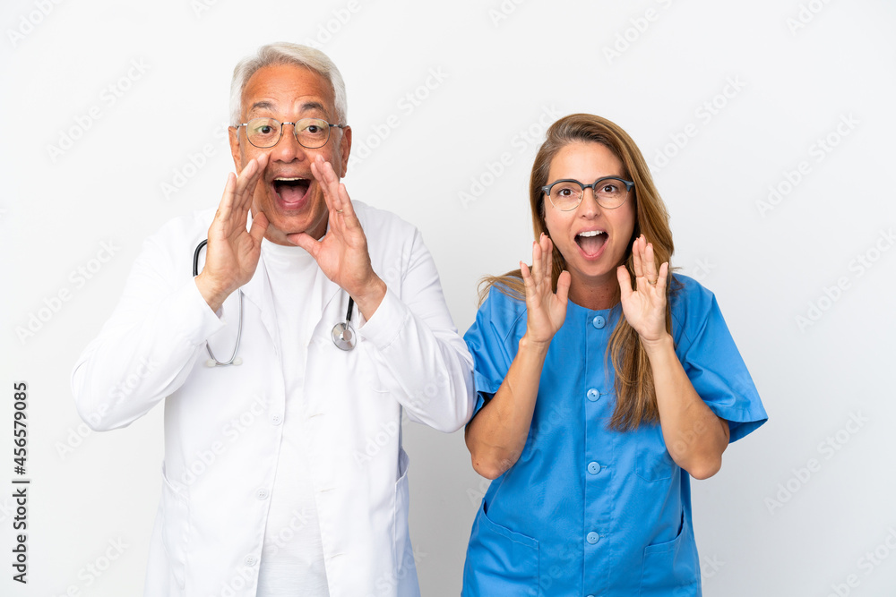 Middle age doctor and nurse isolated on white background shouting and announcing something Middle age doctor and nurse isolated on white background shouting and announcing something