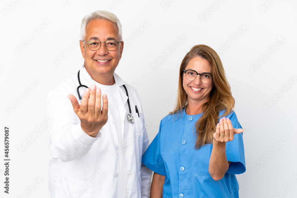 Middle age doctor and nurse isolated on white background inviting to come with hand. Happy that you came Middle age doctor and nurse isolated on white background inviting to come with hand. Happy that you came
