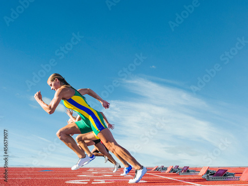 Three female athletes on athletics track, racing