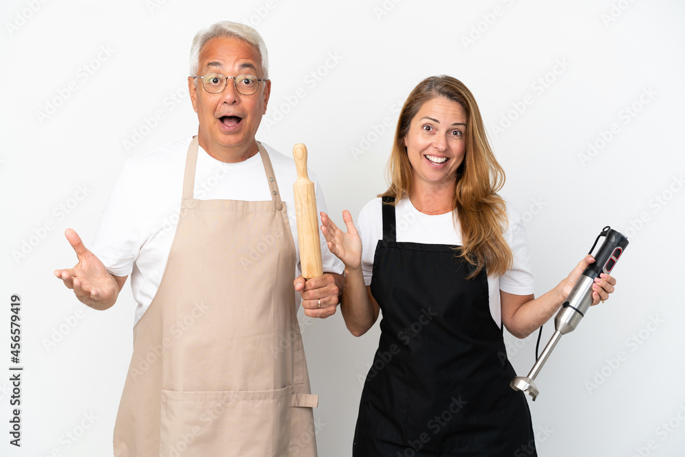 Middle age chefs couple isolated on white background with surprise and shocked facial expression
