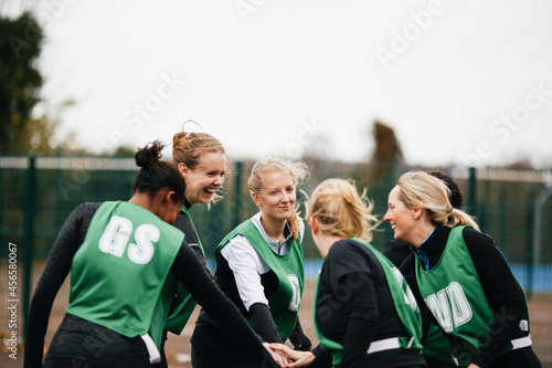 Female netball team shaking hands on netball court
