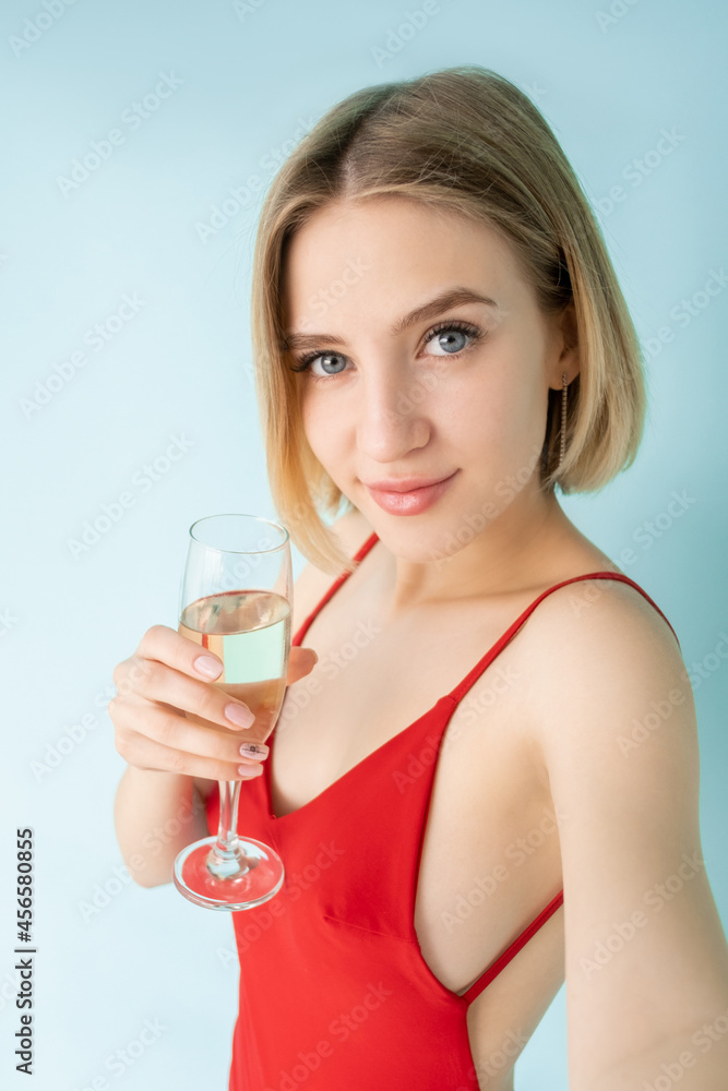 Online stream. Female blogger. Party selfie. Festive look. Pretty happy woman red dress glass champagne make invisible video isolated blue. Online stream. Female blogger. Party selfie. Festive look. Pretty happy woman red dress glass champagne make invisible video isolated blue.
