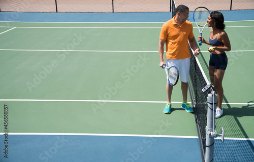 Couple chatting beside tennis court net © Cultura Allies