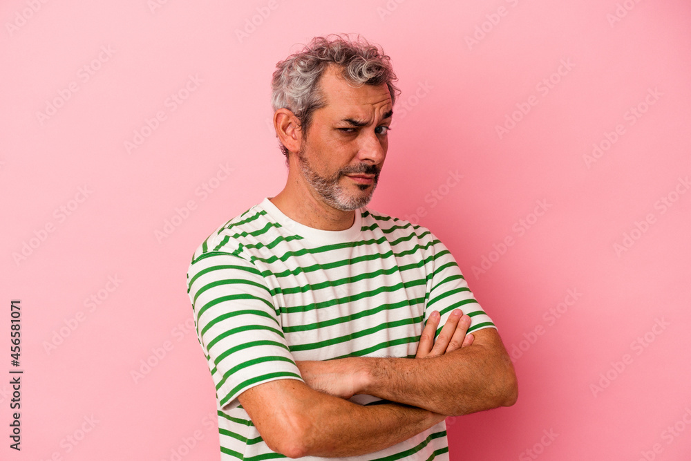 Middle age caucasian man isolated on pink background suspicious, uncertain, examining you. Middle age caucasian man isolated on pink background suspicious, uncertain, examining you.