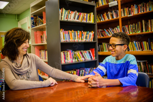 Guidance counselor and teenage boy in school library smiling photo