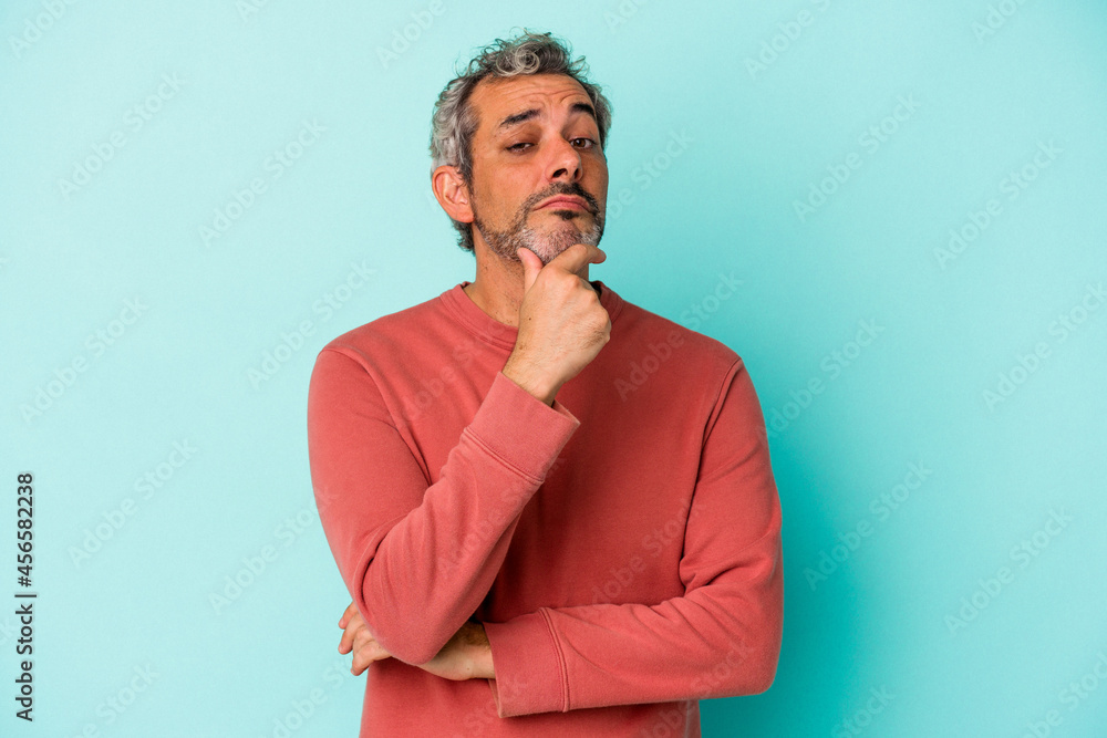 Middle age caucasian man isolated on blue background suspicious, uncertain, examining you. Middle age caucasian man isolated on blue background suspicious, uncertain, examining you.