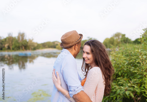 Side view of young couple by lake hugging