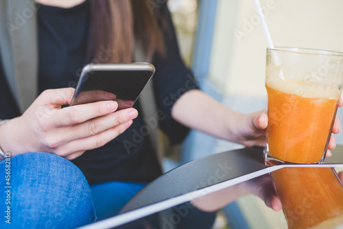 Cropped shot of young woman using smartphone at sidewalk cafe