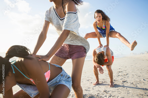 Young man and three female friends playing leapfrog on beach, Cape Town, South Africa