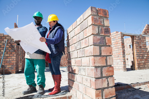 Photos Site manager and builder looking at blueprint on construction site