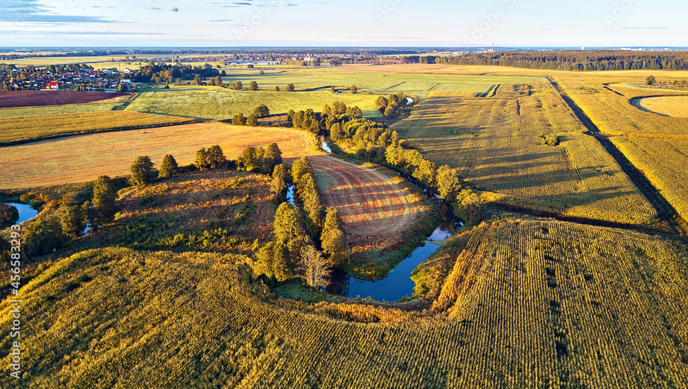 Sunny autumn landscape. Meadows, river, village, dirt road Belarus. Corn harvest.
